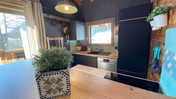 Eine Küche mit Holzarbeitsplatte, einem Blumentopf, einer Pendelleuchte und einem Fenster mit Ausblick.