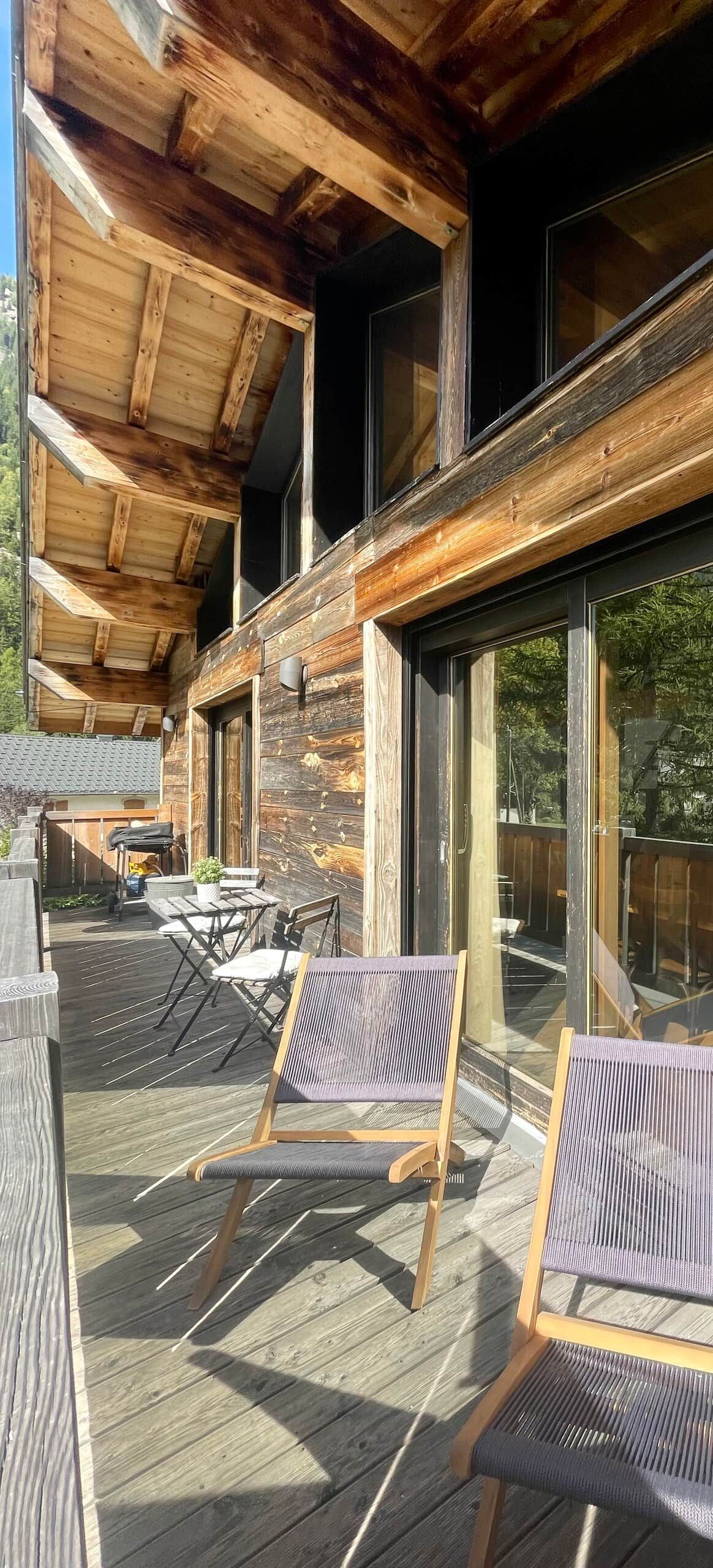 Un patio in legno con posti a sedere all'aperto e ampie finestre.