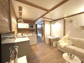 A modern kitchen with wooden beams, a dining area with a sofa and table, and a cozy living space. - Terrace, Mont Blanc view, Chamonix Centre (Chamonix)