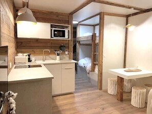 A compact kitchen with a microwave, sink, and wooden accents. - Terrace, Mont Blanc view, Chamonix Centre (Chamonix)