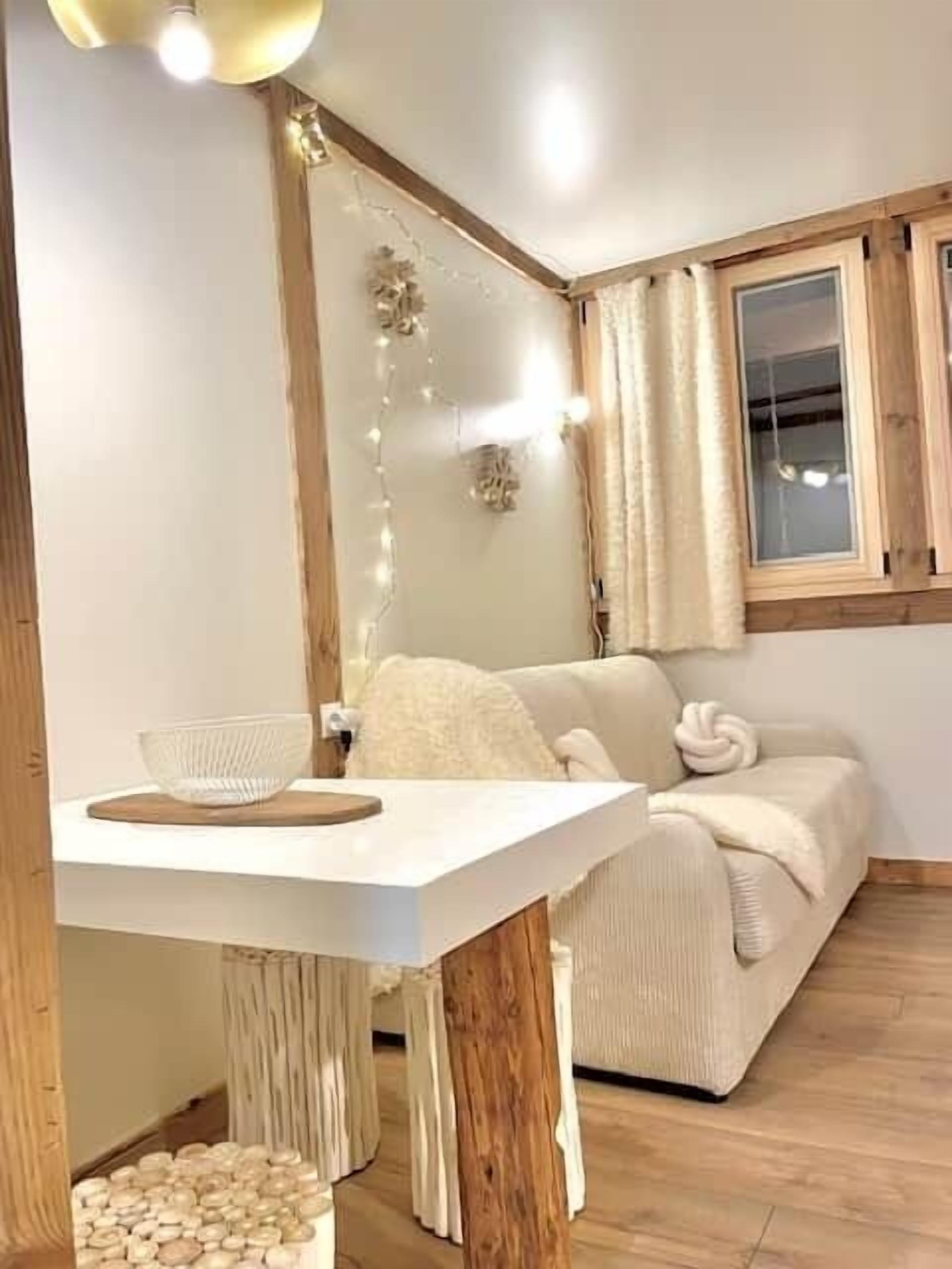 Una habitación acogedora con una mesa blanca, un sofá beige y techo de madera.