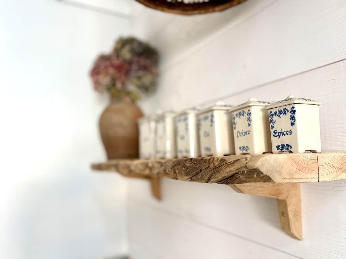 A wooden shelf with spice jars labeled 'Poires,' 'Choux,' and 'Epices.'