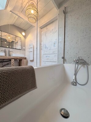 A bathroom with a bathtub, a shower, a sink, and a mirror.