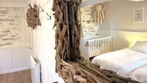 Um quarto rústico com um espelho de madeira grande, um berço branco e uma parede de pedra.