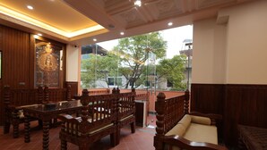 A traditional wooden interior with a balcony, tiled floor, and a large window offering a view of trees and buildings. - Boudha Boutique Inn (Kathmandu)