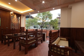 A traditional wooden interior with a balcony, tiled floor, and a large window offering a view of trees and buildings. - Boudha Boutique Inn (Kathmandu)