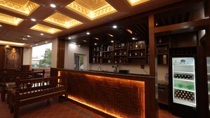 A bar area with a wooden counter, shelves with bottles, and a refrigerator. - Boudha Boutique Inn (Kathmandu)