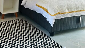 Une chambre à coucher bien rangée, avec un lit, une table de chevet, une lampe et un tapis à motifs.