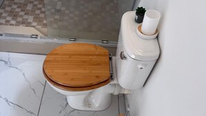 Une salle de bain comprenant des toilettes, un espace douche et un lavabo.