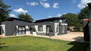 Une maison moderne à deux étages, dotée d’un toit plat, d’un patio couvert et d’une pelouse bien entretenue.