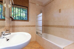 Une salle de bain avec un lavabo, une baignoire et une fenêtre.