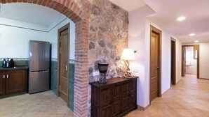 A kitchen with a stone wall, a refrigerator, cabinets, and a countertop. - Masia Garriga (Tarragona)