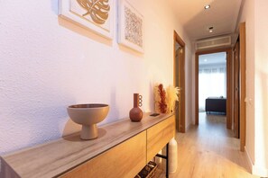 Un pasillo con una consola de madera, un cuenco, un florero y objetos decorativos.