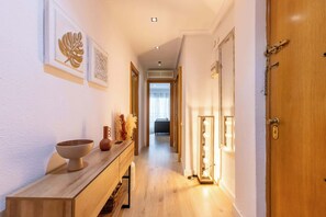 A hallway with a wooden bench, wall art, and a vanity with a mirror and lights. - City Center · Ritort - Unik Vacation (Tarragona)