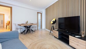 A modern living room with a flat-screen TV, wooden panel wall, and a dining area with a table and chairs. - City Center · Ritort - Unik Vacation (Tarragona)
