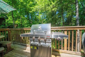 Een Char-Briil grill voor commercieel gebruik op een houten terras met een houten balustrade en een picknicktafel.