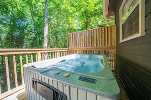 Ein Whirlpool auf einer Holzterrasse mit Blick auf einen Wald.