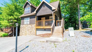 A two-story house with a stone foundation, a wooden deck, and a front porch. - Bear Cozy: Snuggle Up in the Smokies (Pigeon Forge)