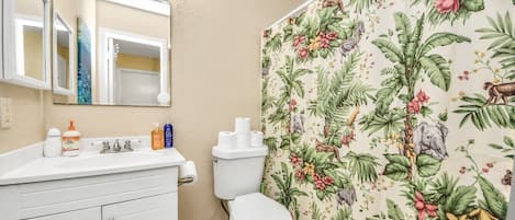 A bathroom with a toilet, sink, and mirror.