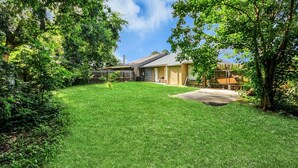 A residential backyard with a house, a lawn, and trees. - Lofty Grace Home 3 - Houston (Houston)