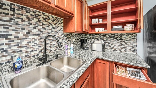 A kitchen with a double sink, a coffee maker, a toaster, and wooden cabinets. - Lofty Grace Home 3 - Houston (Houston)