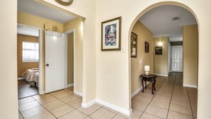 A hallway with a clock, framed artwork, and a door leading to a bedroom. - Lofty Grace Home 3 - Houston (Houston)