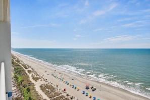 Ein Strand mit Sonnenschirmen, einem klaren Himmel und dem Meer.