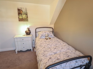 Ein Schlafzimmer mit einem Bett, einem Nachttisch, einer Lampe, einem Wandbild und einem Teppichboden.