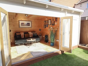 A cozy wooden interior with a sofa, a small table, and a potted plant. - 4 Eve Street (Louth)