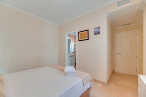 Ein Schlafzimmer mit einem Bett, einer Tür und einem kleinen Badezimmer, das durch eine geöffnete Tür sichtbar ist.