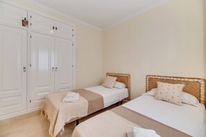 Een slaapkamer met twee bedden, een kledingkast en een badkamer.