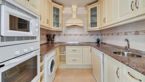 A kitchen with white cabinets, a microwave, oven, washing machine, and a sink. - LXR Atlantida 3-Bedroom Near the Ocean (Fuengirola)