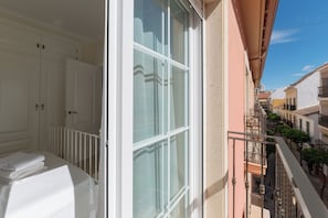 Ein Balkon mit Blick auf eine enge Straße, eine weiße Tür und ein weißes Geländer.