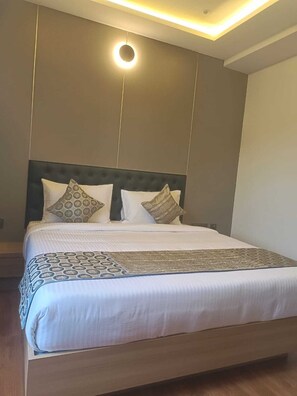 Habitació d'hotel moderna amb un llit gran, una làmpada de sostre rodona i un disseny minimalista.