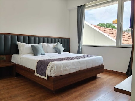 A bedroom with a bed, wooden headboard, and a window with curtains.. LG CORDIAL