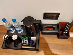 La nevera minibar d'una habitació d'hotel amb aigua embotellada, cafè, te, aperitius i un comandament a distància.