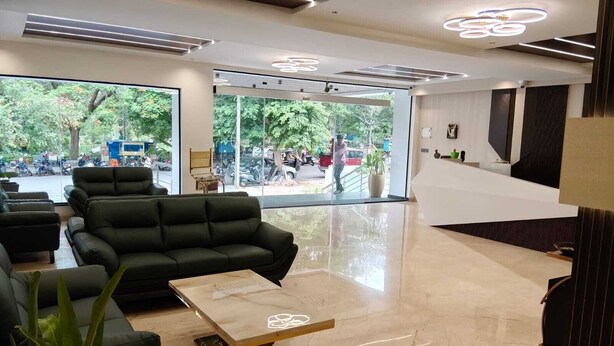 A modern reception area with a sofa, a coffee table, and a reception desk. - LG CORDIAL (Mysore)