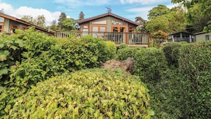 A two-story house with a balcony, surrounded by dense greenery. - Troutbeck Lodge (Keswick)