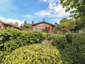 A two-story house with a balcony, surrounded by dense greenery. - Troutbeck Lodge (Keswick)