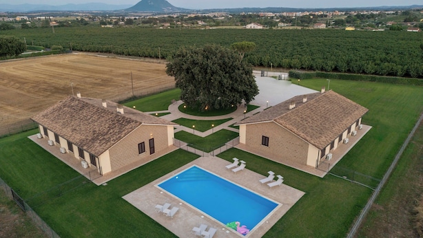 Un'ampia tenuta con piscina, due edifici principali e una montagna sullo sfondo.