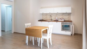 Una cucina moderna con mobili bianchi, un tavolo di legno e un forno integrato.