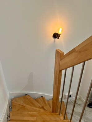 Eine Holztreppe mit einer Wandleuchte.