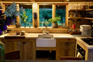 A wooden kitchen with a window, a sink, and various kitchen items.