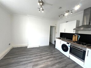 Eine moderne Küche mit Waschmaschine, Backofen und Dunstabzugshaube aus Edelstahl.