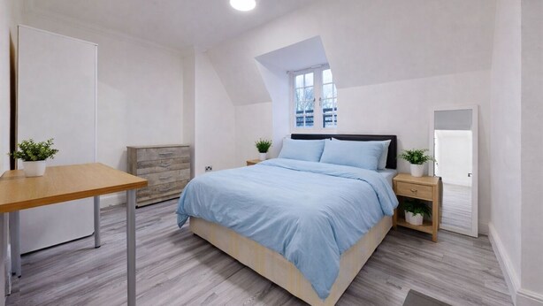 A bedroom with a bed, bedside tables, a desk, a window, and a door. - Discover This Spacious Living Space Kings Cross (London)