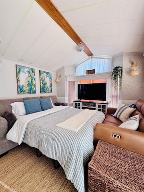 A bedroom with a bed, a sofa, a TV, and artwork on the walls.