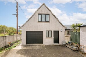 Ein eingeschossiges Gebäude mit Garage, einer kleinen Tür und einem Fenster.
