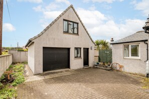 Ein eingeschossiges Gebäude mit Garage, kleiner Terrasse und einem Fahrrad.