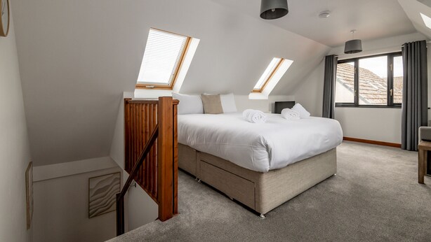 Ein Schlafzimmer mit Bett, einer Holztreppe und Dachfenstern.