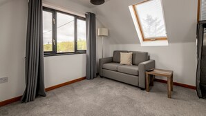 Ein modernes Wohnzimmer mit einer Couch, einem kleinen Tisch, einer Lampe und einem Oberlicht.